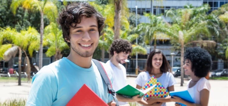 A man smiling and a group of students talking, on a college tour