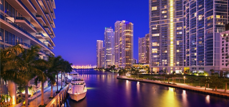 nighttime miami skyline with boat and water