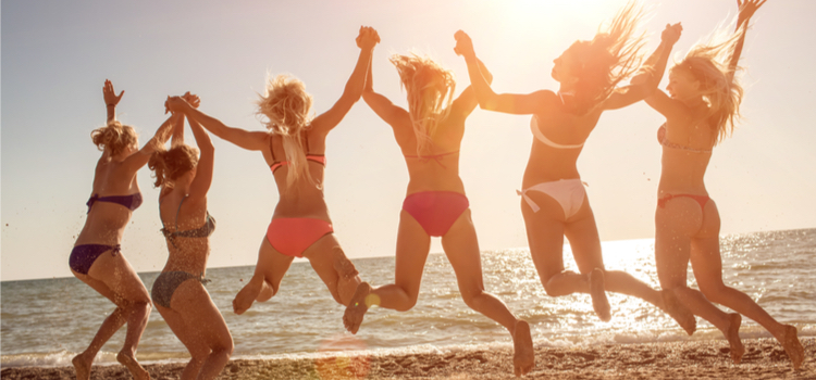 group of six girls jumping on the beach