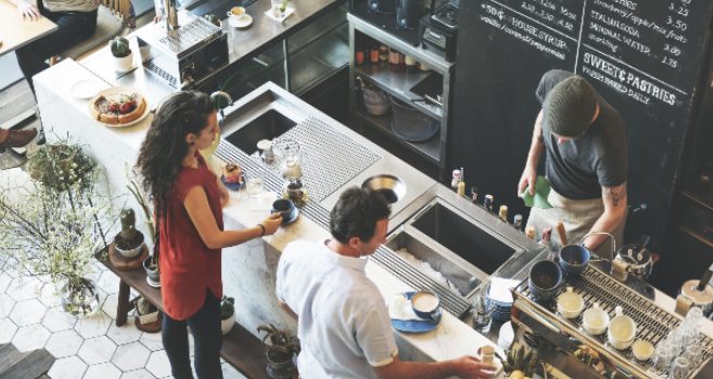 Two people at a coffee shop talking to a barista and placing an order.